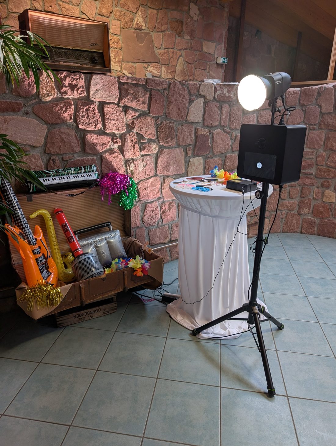 Aufgebaute Fotobox mit Stehtisch und Requisitenkiste auf einer Feier