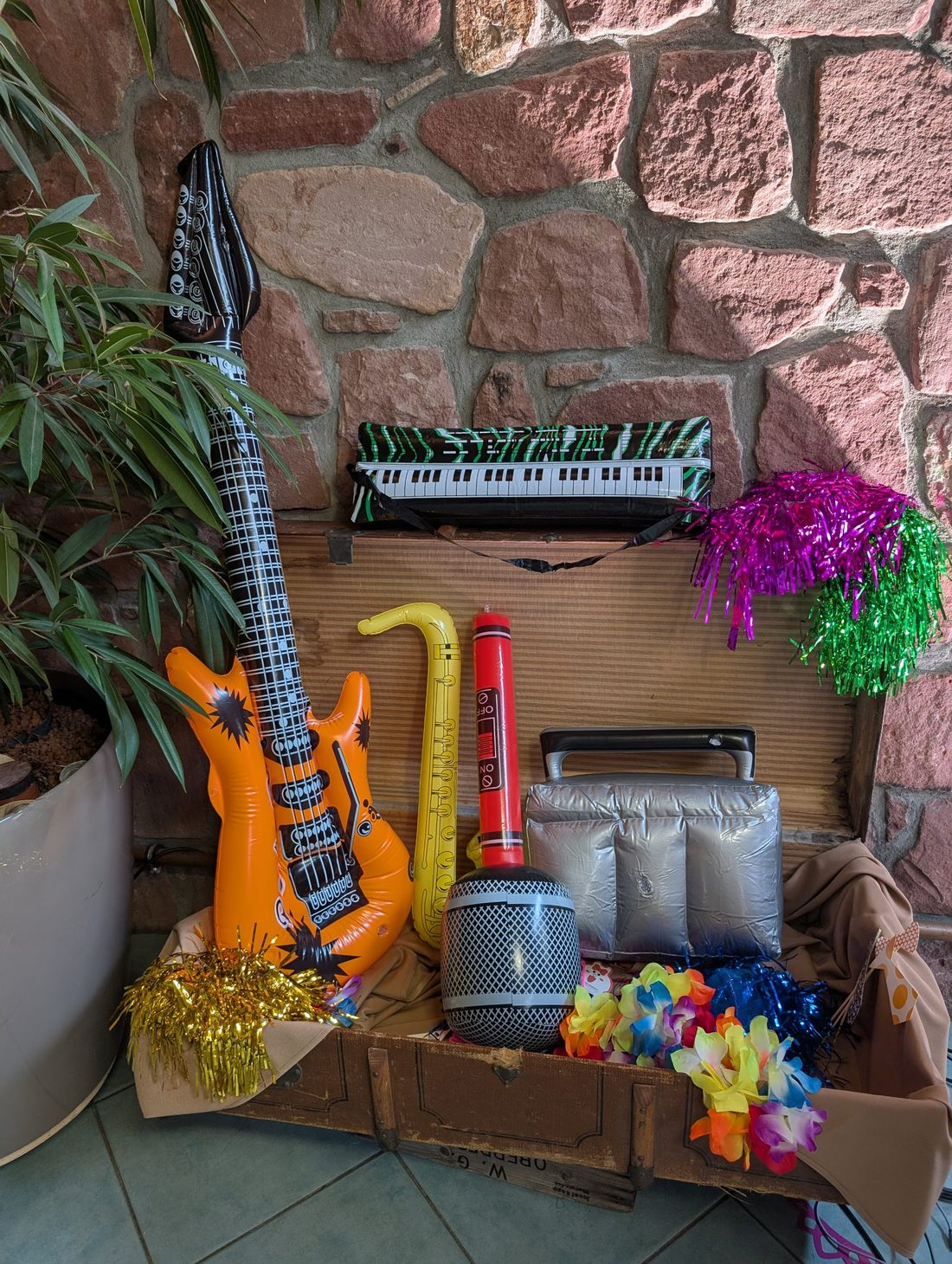 Kiste mit Requisiten: aufblasbare Gitarre, Saxofon, Mikrofon, Perücken und Blumenketten